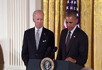 President Obama speaking at podium with VP Joe Biden standing behind him