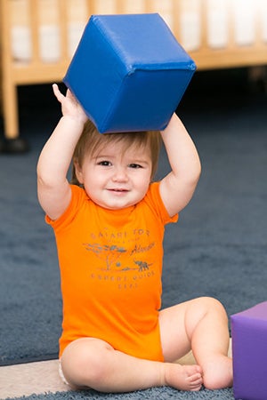 A baby with a blue toy block