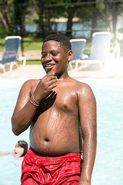 A teenager smiling in front of a pool
