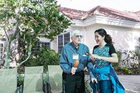 An elderly man and a caregiver outside