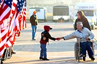 A veteran in a wheelchair with a young caregiver and a little boy