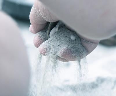 Child at beach, running sand through hand