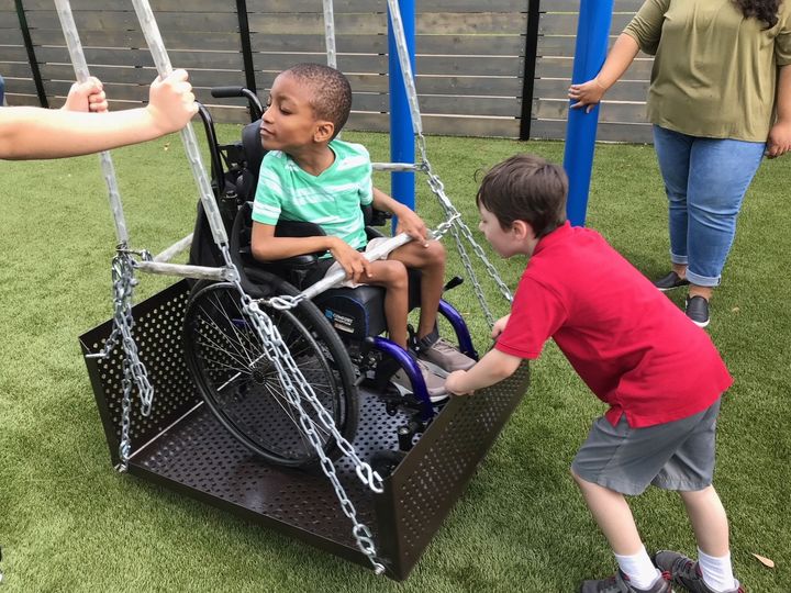 An African American child, male, using a wheelchair and adaptive swing