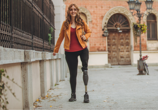 A woman with a prosthetic leg smiling, walking outside