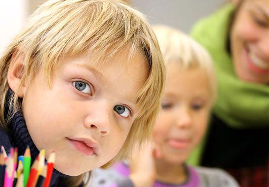 A child in a classroom, looking at the camera