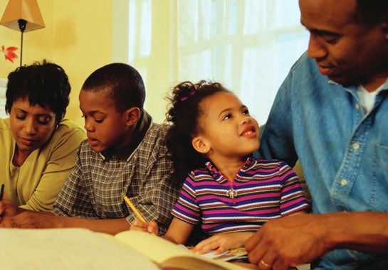 Family sitting around a table reading