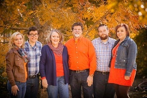 The Gaither family outside with fall foliage in the background