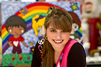 Haley Moss smiling in front of a mural featuring a rainbow in the background