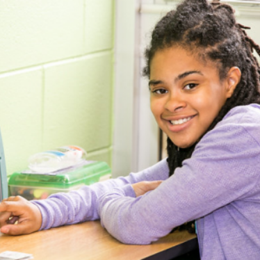 young girl smiling in front of computer
