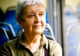 an older woman is sitting in a bus looking out the window