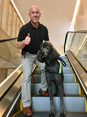 Tim and Colton, a poodle, on an escalator.
