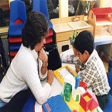 A Behavioral Therapist working with a kid teaching them modeling 