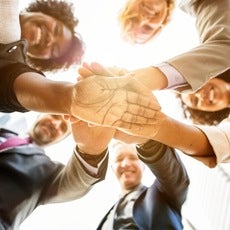 A group of diverse corporate coworkers putting their hands in a circle 