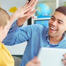 A black Behavioral Therapist high fives a student 