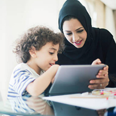 A Muslim mother and son using an AAC device together 