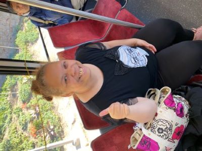 Bianca wearing a black shirt, sitting on the bus and giving a thumb's up
