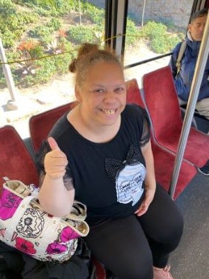 Bianca wearing a black shirt, sitting on the bus and giving a thumb's up