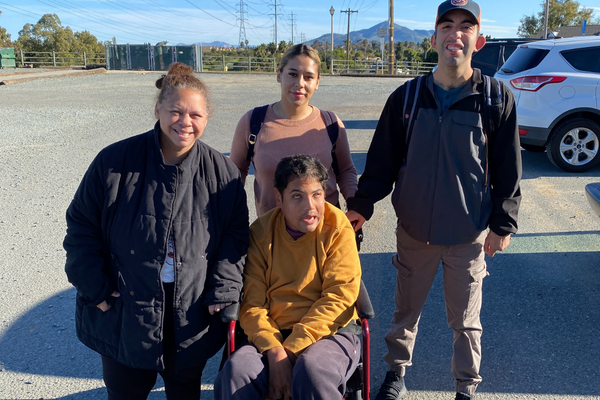 Bianca (left) with two male participants accompanied by a Life Skills Coach smiles at the camera and out in the community. 