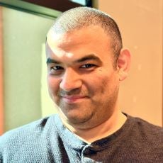 A smiling man in a grey shirt