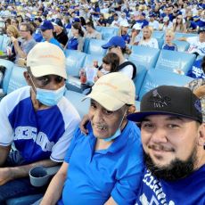 Three men in baseball hats at a stadium enjoying a baseball game