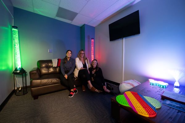 Three representatives pose in the Autism Sensory-friendly room at the Angel's stadium