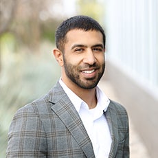 Photo shows man with beard and green shirt smiling 