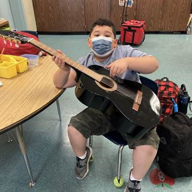 Photo of Autism Services Participant Adan playing guitar 