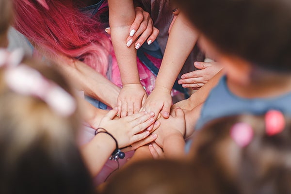 circle of children's arms reaching into center of circle.