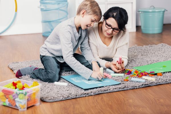 Woman and boy drawing together on the floor