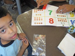 Little boy looks at the camera as his therapist shows a book on counting