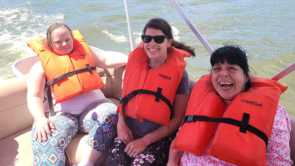 Three women with life vests in boat on the lake