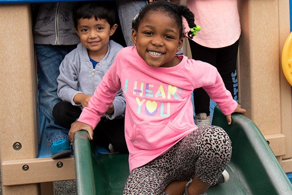 African American girl sitting at the top of the playset slide