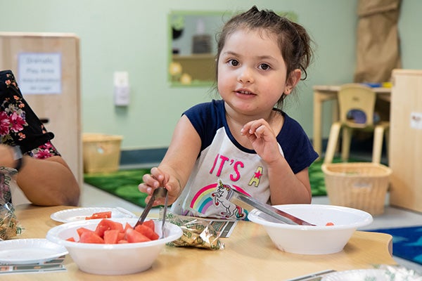 Preschool girl cooking at table