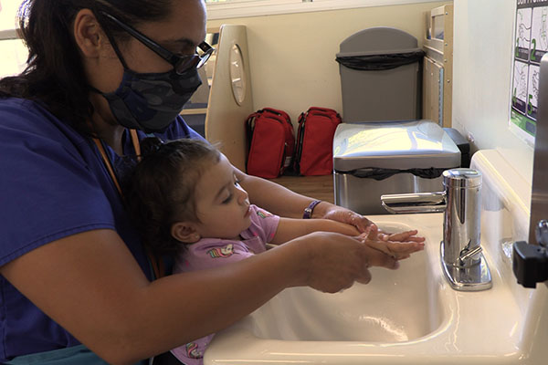 Educator helping child wash her hands