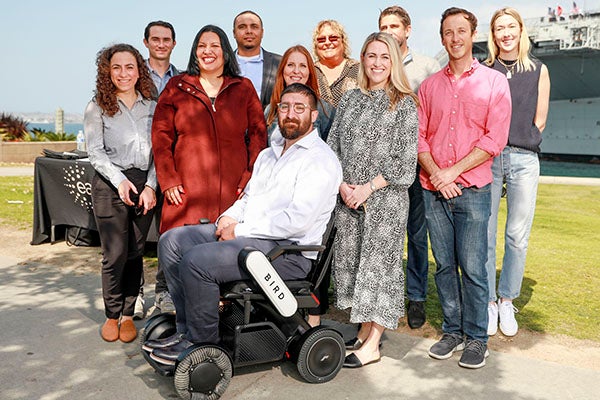 Group photo of Easterseas and Bird representatives in front of Veteran Nick Voss in Bird Power Wheelchair