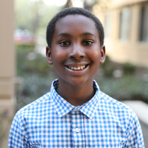 A photo of former Autism Therapy Services participant, Evan wearing a blue button up smiling for a photo.