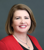 A white woman with brown hair wearing a red blazer and black blouse smiling for her headshot