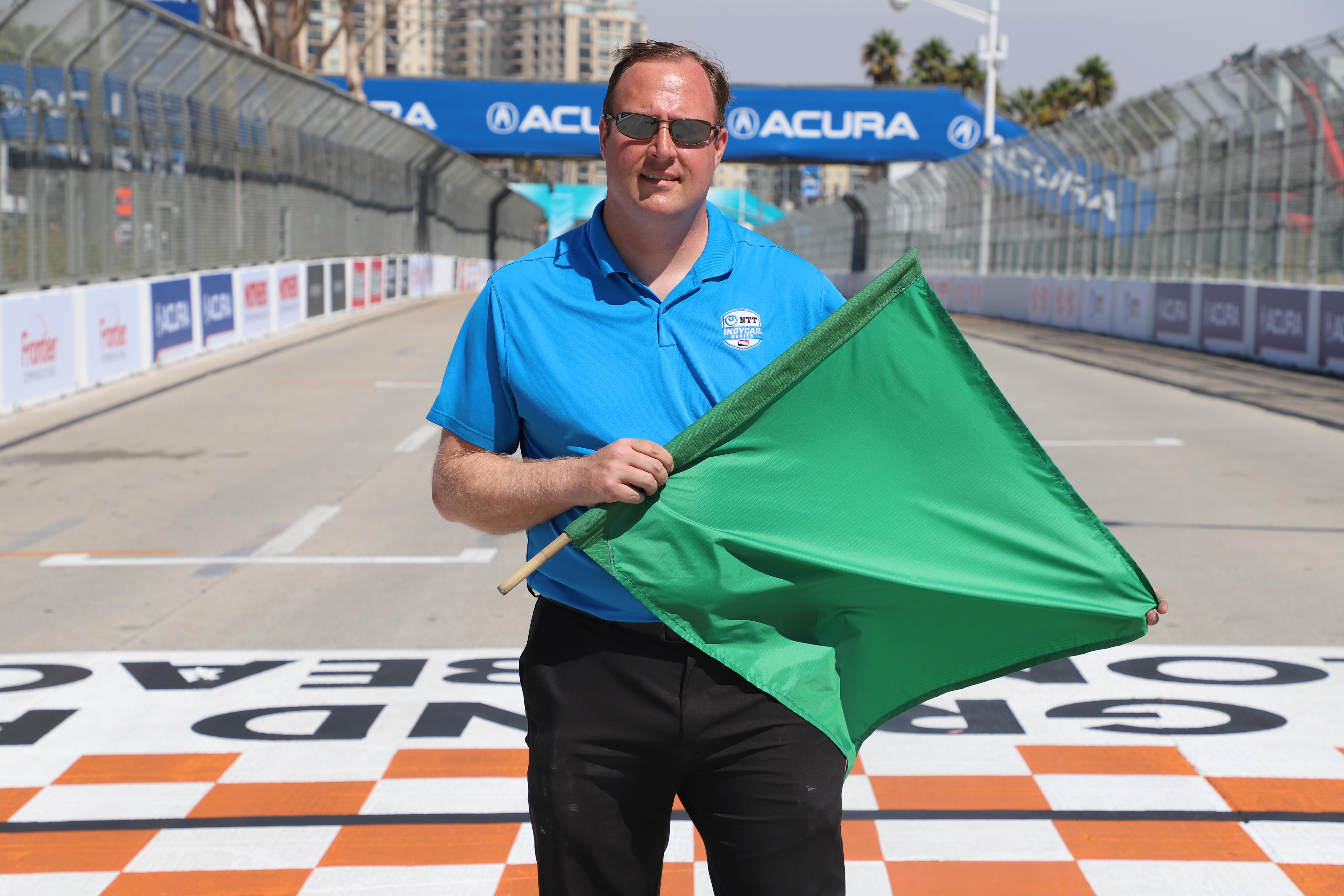 Photo features Aaron Likens holding green flag at starting line