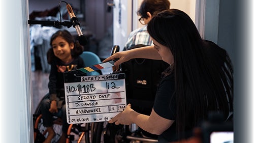 Girl in wheelchair on film set behind slate