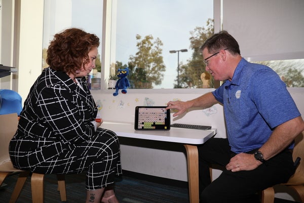 Bruce Fleming (right) demonstrates the Wego 10A communication device for Natalie Jauregui.