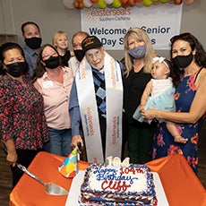 Cliff stands in front of his birthday cake with family and ESSC associates