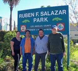 Four volunteers stand beneath the Ruben F. Salazar Park sign