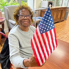 Elderly lady sitting holding an American flag