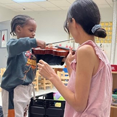 Ms. Saori teaching Azir to play violin