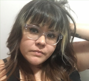 A latinx woman with long hair and glasses looking squarely at the camera