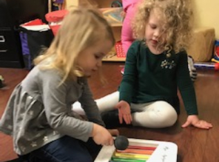 Two girls sitting playing the xylophone