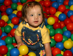 Toddler in a ball pit smiling 