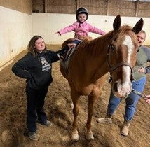 Little girl on horse with two guides